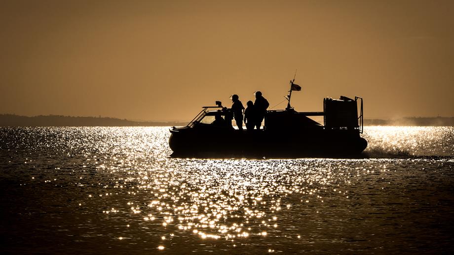 Southend-on-Sea’s hovercraft, Vera Ravine, during an evening training exercise. The hovercraft is silhouetted on a sparkling sea. 