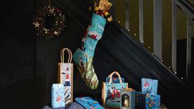 A Christmas stocking and side table are festively decorated beside a staircase – both are filled to the brim with RNLI goodies
