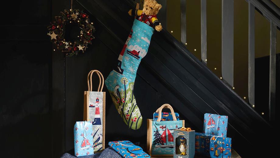 A Christmas stocking and side table are festively decorated beside a staircase – both are filled to the brim with RNLI goodies