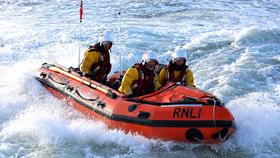 Three crew members aboard Calshot’s D class lifeboat in heavy surf 