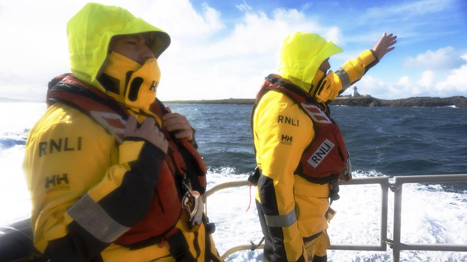 Two crew members from Ballyglass RNLI on their Severn class lifeboat, wearing their hoods up to protect against the weather and sea spray