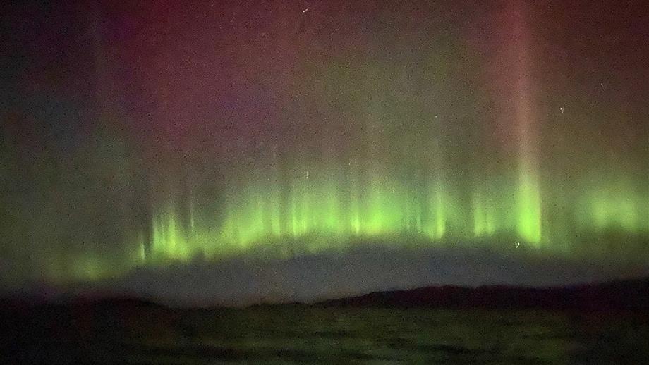 The green and pink light of the aurora borealis across the sky at Kyle of Lochalsh