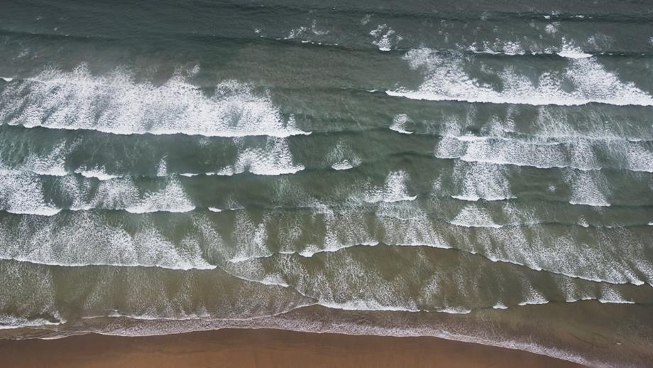 The flatter channel of water in between the white breaking waves at the centre of this photo is a rip current