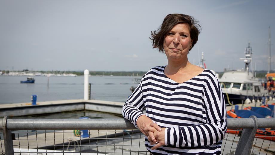 A woman in a striped top stands next to the lifeboat dock at the RNLI College