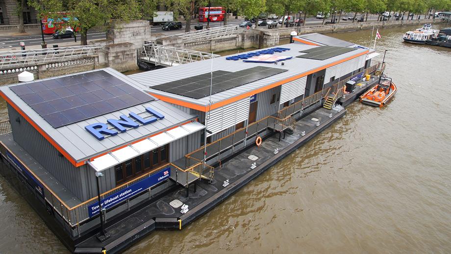 The grey and orange exterior of Tower Lifeboat Station, floating on the River Thames