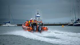 A B class lifeboat heading out of the harbour on a grey, stormy day