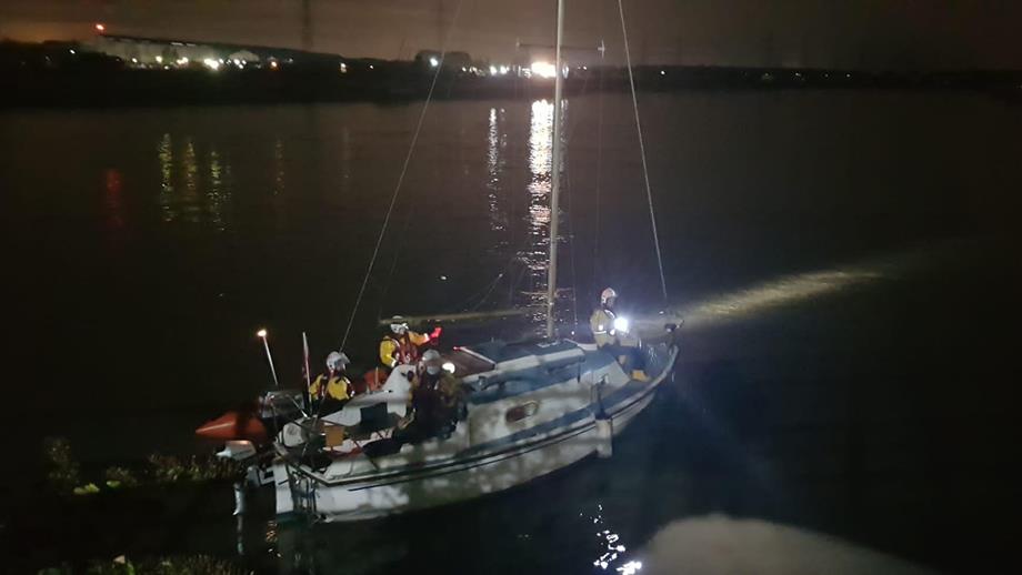 The Flint RNLI crew, in their D class lifeboat, are alongside a yacht. It’s a dark night.
