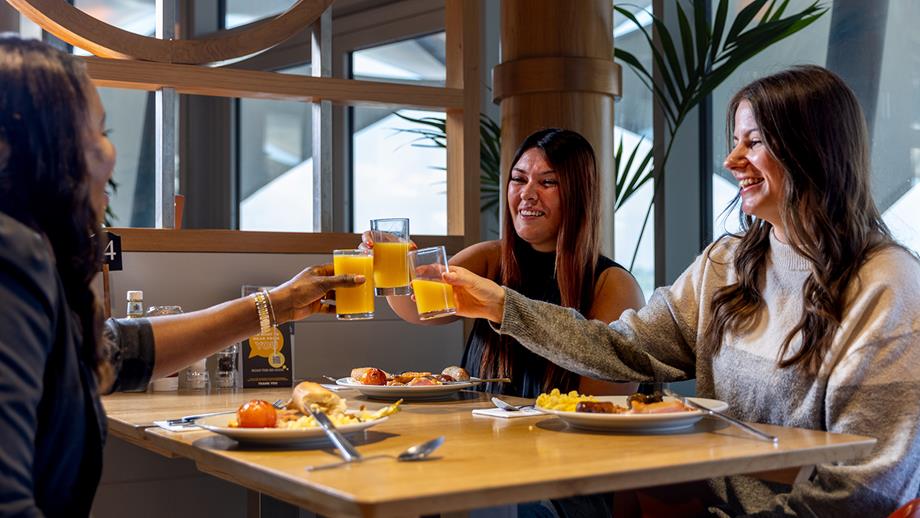 Three women sitting in the RNLI Riggers Restaurant, clinking their glasses
