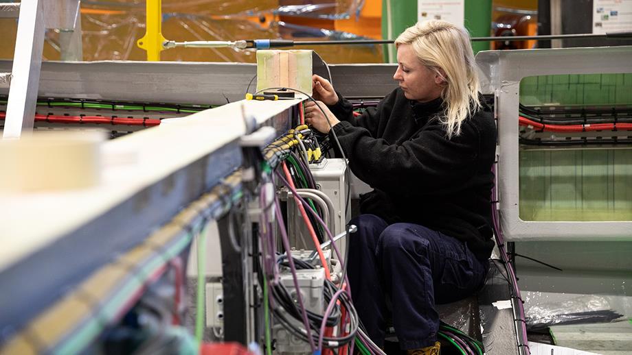A woman is installing multi-coloured hull cables to the Shannon class lifeboat in the All-weather Lifeboat Centre