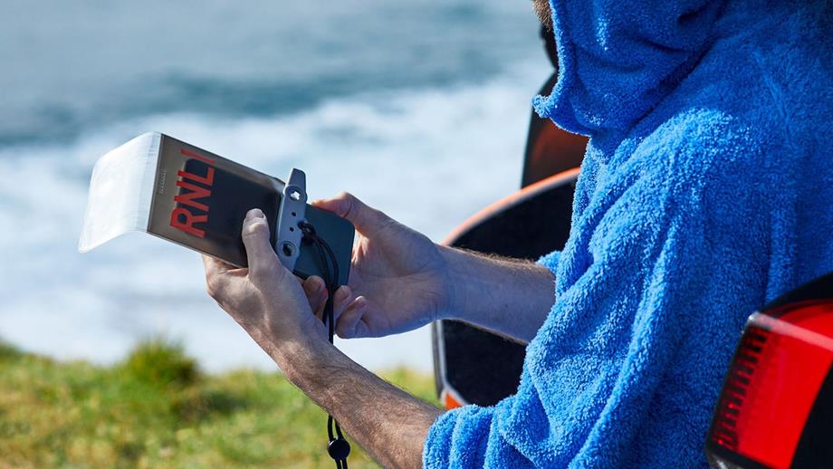 A man wearing a blue changing robe, holding a waterproof phone pouch in his hands