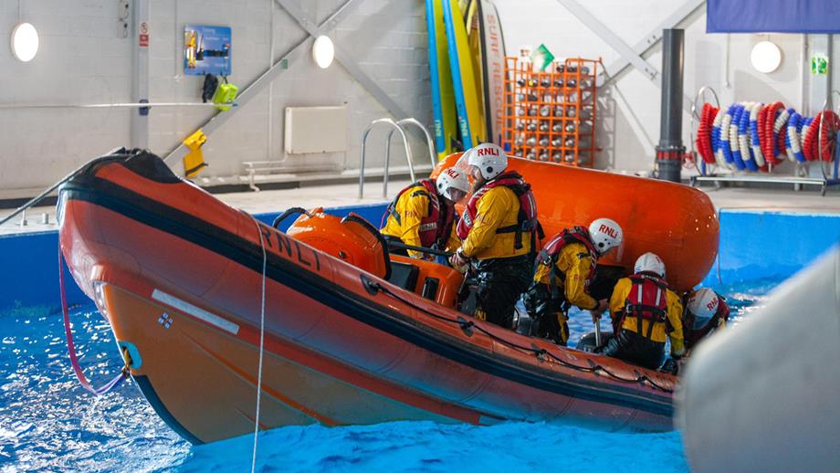 Four crew members aboard an inshore lifeboat in the RNLI’s sea survival pool