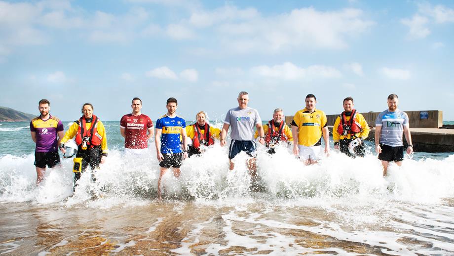 GAA sports stars stand in the breaking surf alongside lifeboat crew members from Red Bay