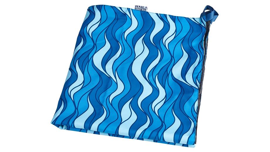 A blue towel with a printed wave pattern, packed down into a small square