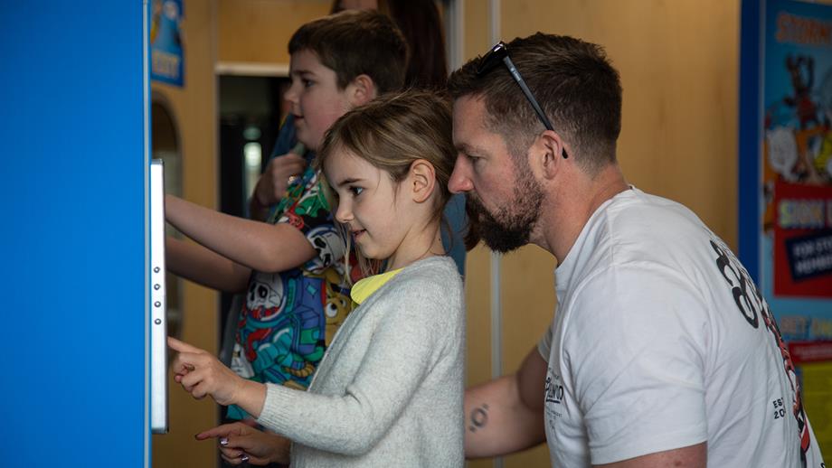 Two children and their parents playing Storm Force Rescue on the touchscreens at the Lifeboat Festival in Poole.