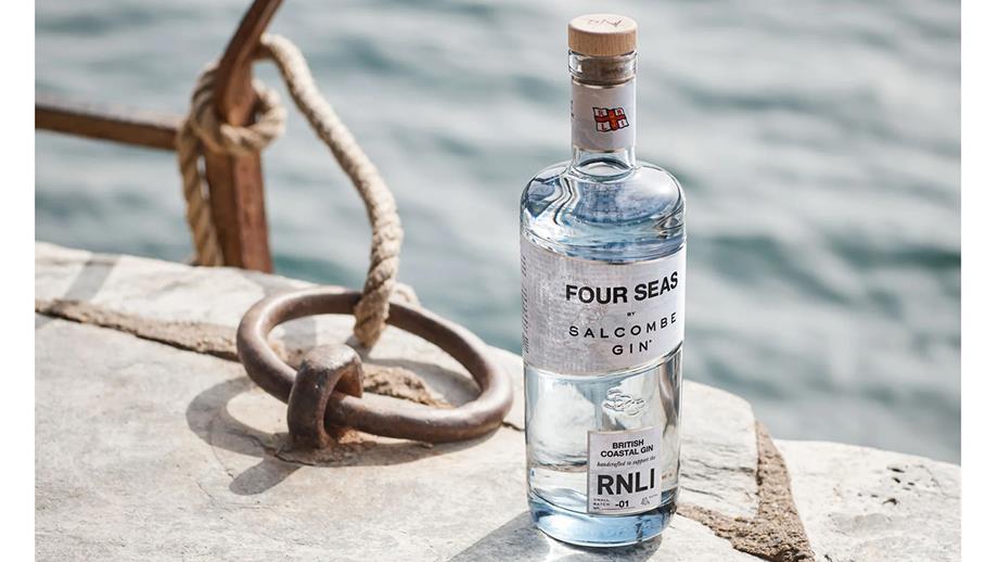 A bottle of Salcombe Gin’s Four Seas gin rests on a harbour wall next to a mooring ring