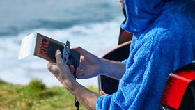 A man holding a clear waterproof phone pouch, with RNLI printed across the front