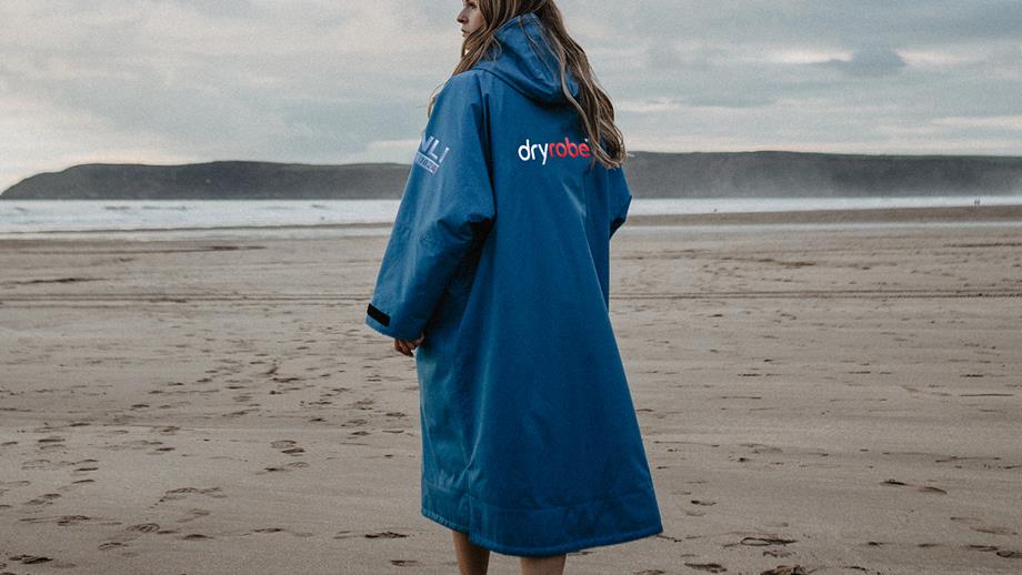 A woman on a beach wearing a blue and black long-sleeved changing robe 