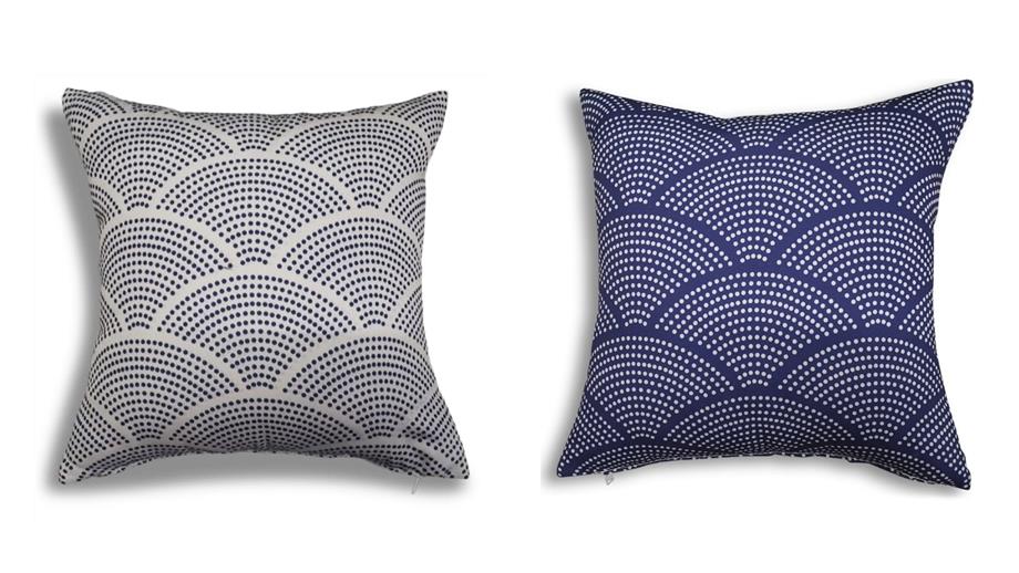 A cushion patterned with radiating and overlapping dotted circles that resemble stylised fish scales. Shown twice: blue dots on white and white dots on blue.