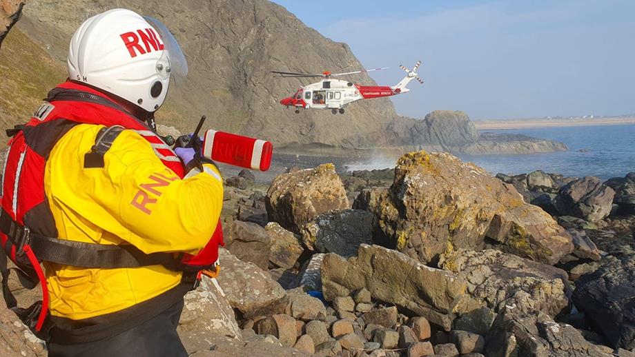Anstruther Lifeboat Crew Member Stuart Hoggan watching on from the rocks as the Coastguard rescue helicopter comes into land on the adjacent beach. 