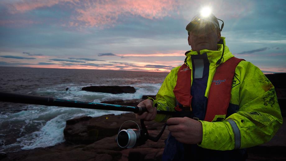 An angler wearing a lifejacket while fishing on the rocks