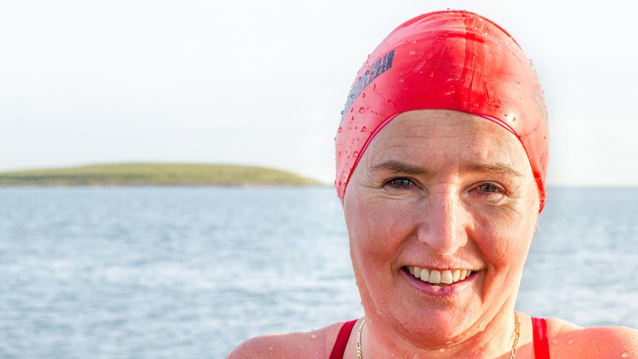 Catherine smiles at the camera, wearing a red swimming cap