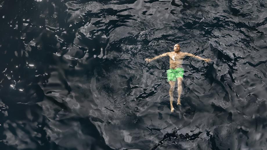Man floating with ears submerged and arms outstretched