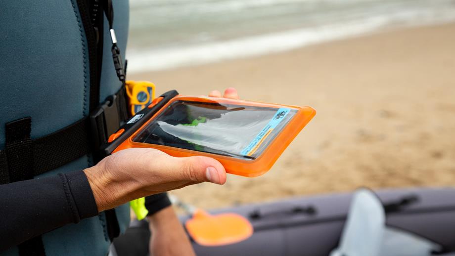 A man is holding a mobile phone in a waterproof case