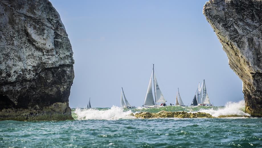 Two large rocks in the sea are in the foreground of the image, framing several sailboats in the background