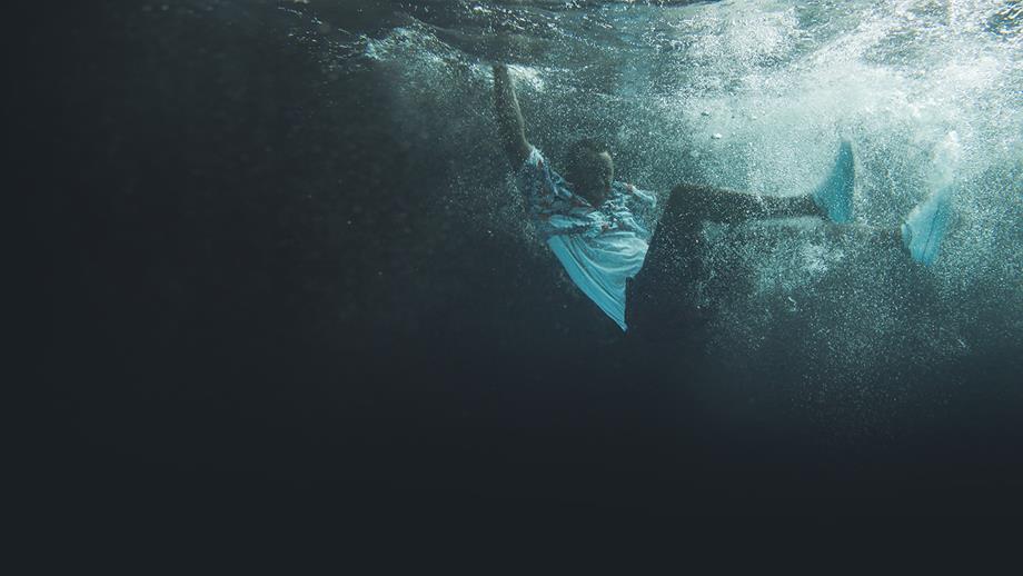 A fully-clothed man underwater after falling into the water