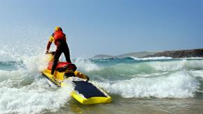 RNLI lifeguard crashing through the surf on a rescue watercraft