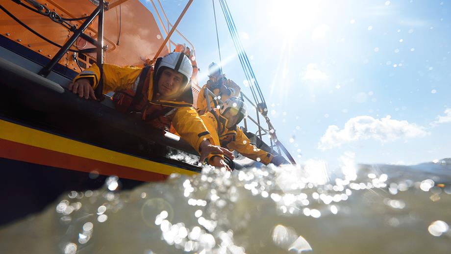 Humber lifeboat crew reaching out from the boat toward a casualty in the water