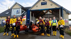 The crew at Wexford RNLI stand in front of the boathouse, next to their inshore lifeboat