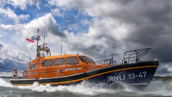 A lifeboat speeds across choppy waters under a stormy sky.