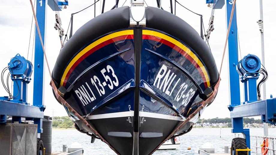 A Shannon class lifeboat is suspended over the water by a crane in preparation for being lowered to commence sea trials