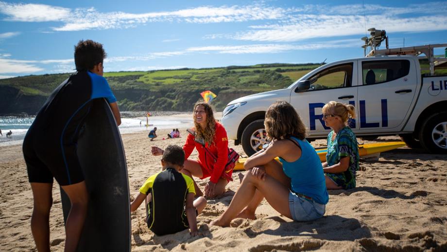 Lifeguards sitting on a beach with member of the public sharing safety advice