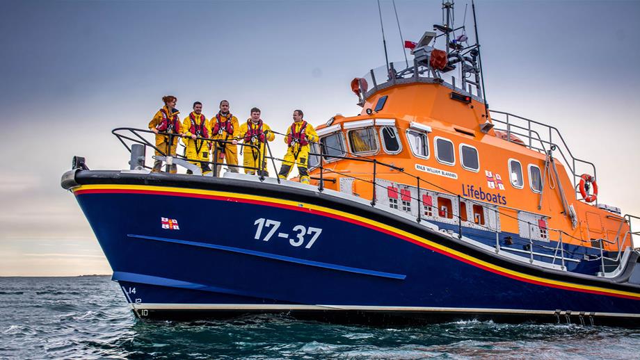 Buckie RNLI’s Severn class all-weather lifeboat on a calm sea with five crew members on deck, some looking toward the camera