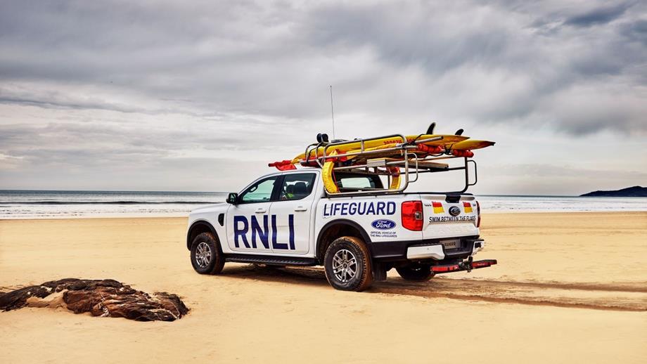A white Ford Ranger with RNLI Lifeguard written on the side and rescue boards on the roof rack.