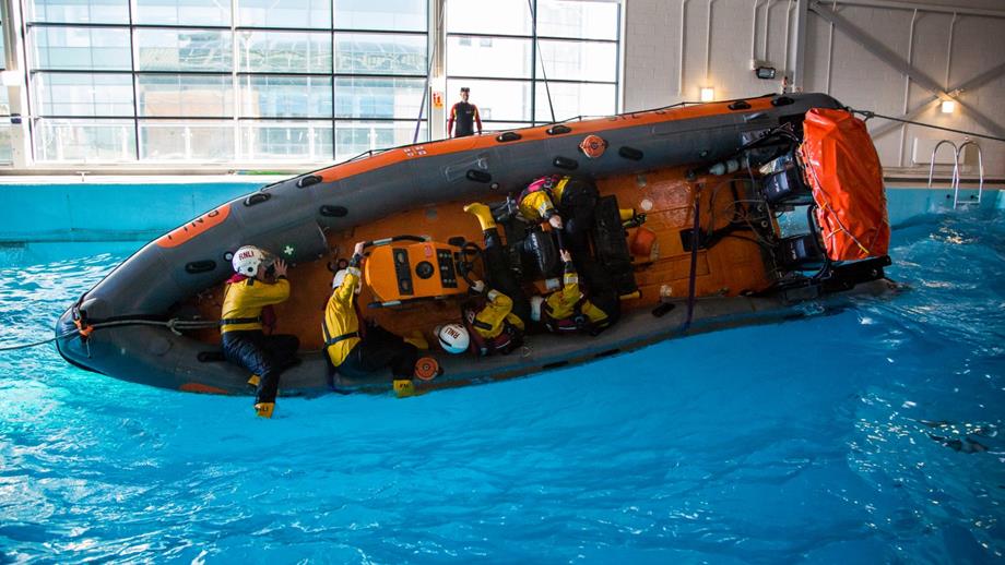 Trainee crew members practising a capsize in a B class inshore lifeboat in the Sea Survival Pool at RNLI College