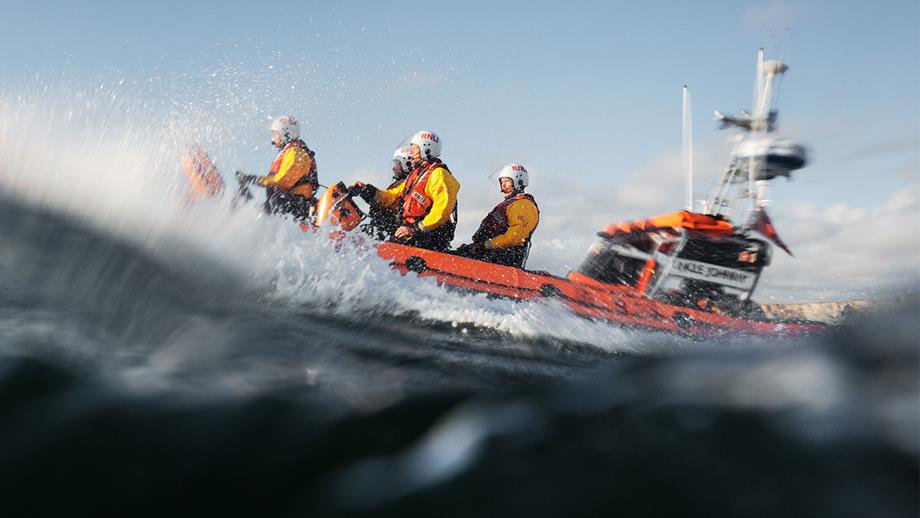 An Atlantic 85 inshore lifeboat with four crew members onboard pushes through foaming waves
