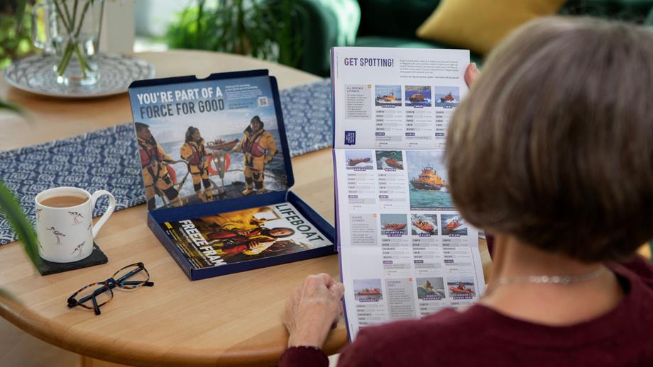 RNLI Supporter opening their membership pack, reading magazine and brochure.