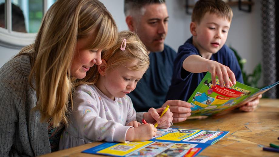 A young family sat at a table reading the Stormforce magazine, and completely the Stormforce activities. 