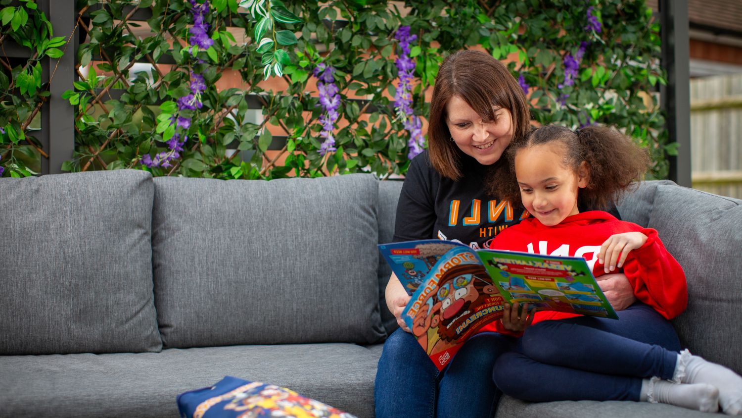 A woman and child reading the Stormforce magazine together in a garden.