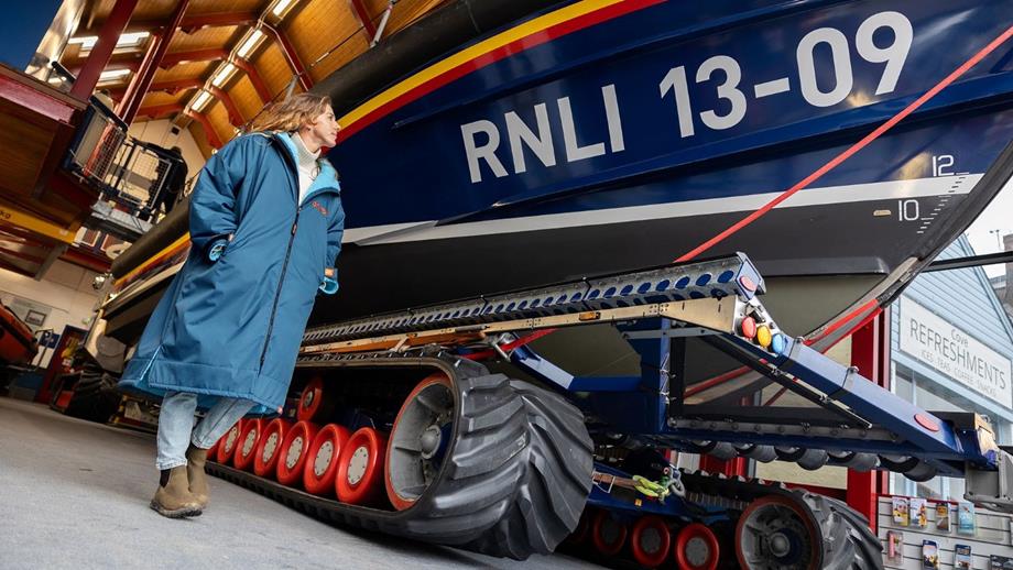 A woman in a blue Dryrobe stands by a lifeboat