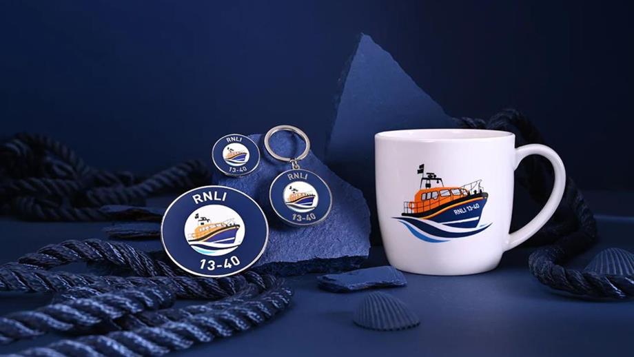 A mug and pin badges depicting an orange lifeboat are displayed on blue background