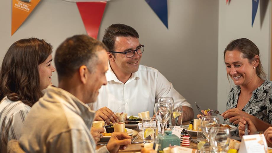 A group of people are sitting at a table enjoying an RNLI fish supper