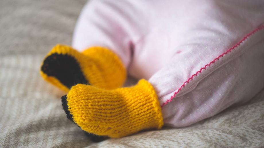 A baby wearing knitted RNLI yellow wellies!