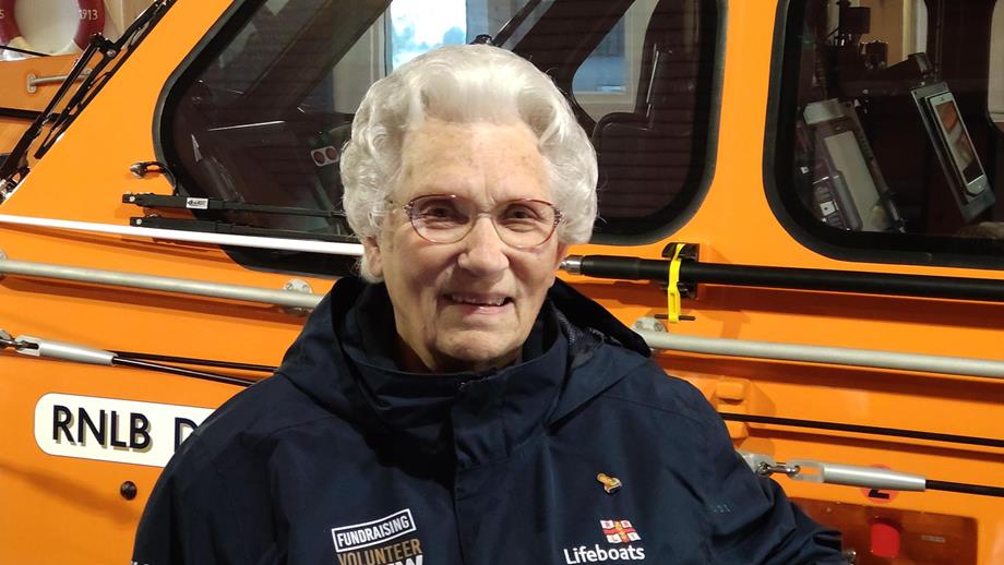Wells RNLI Fundraising Volunteer Sheila Warner MBE standing in front of the station’s Shannon class all-weather lifeboat inside the boathouse