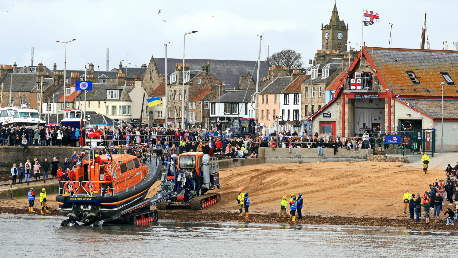 The Anstruther Shannon lifeboat being brought back onto shore by tractor in front of the lifeboat station and a large supportive crowd.