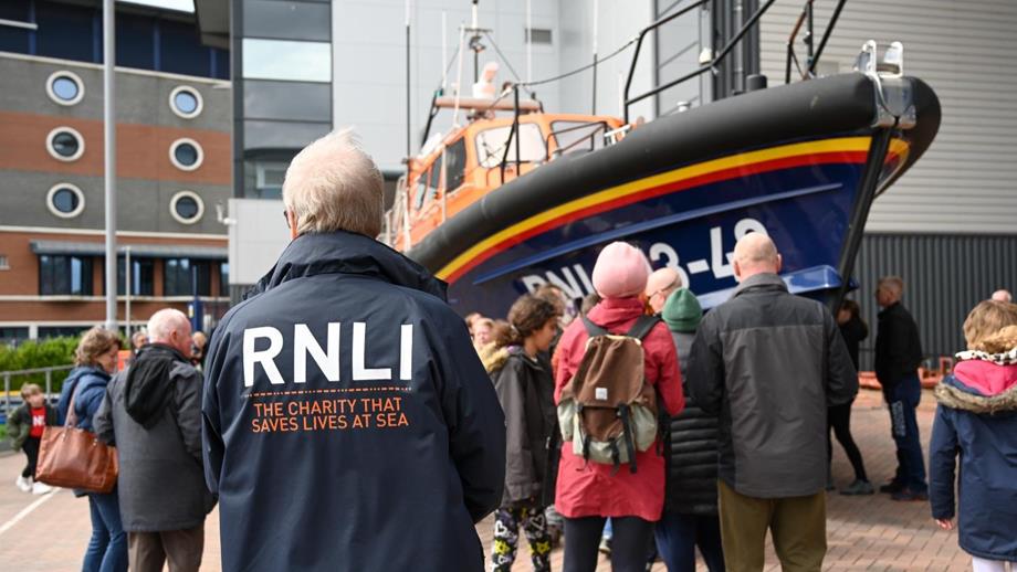 People standing round a RNLI lifeboat at a Launch a Memory event, viewing their loved one's name.