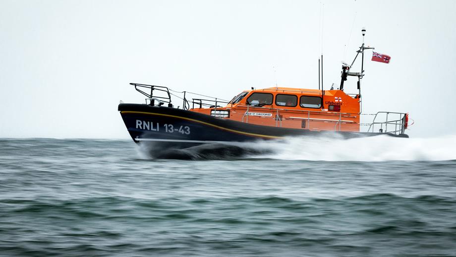 A Shannon class lifeboat is moving fast out at sea on a cloudy day.